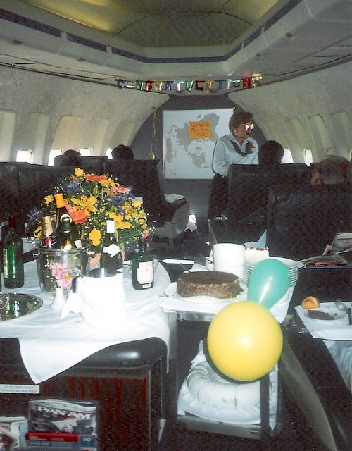 1980s Purser, Peggy Catalano, on her last working flight before retirement.  The crew threw a party in-flight from Rome to New York complete with balloons and banners.  Here Peggy is seen offering dessert from the cart in the First Class cabin of a Boeing 747.